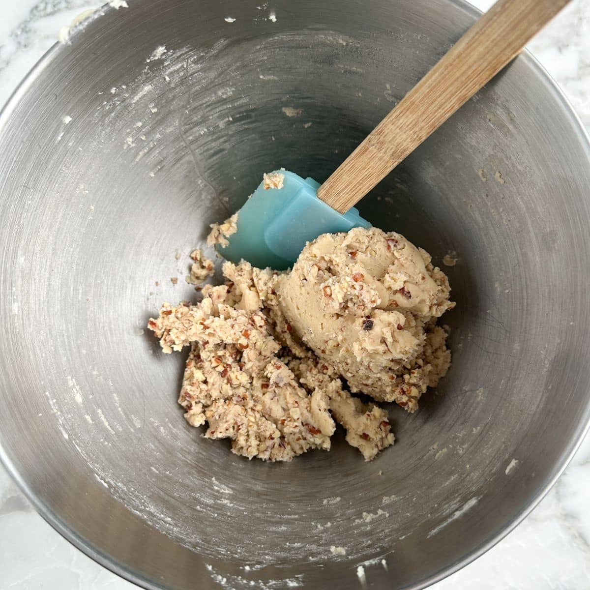 Mixing bowl with pecan balls batter and a spatula. 