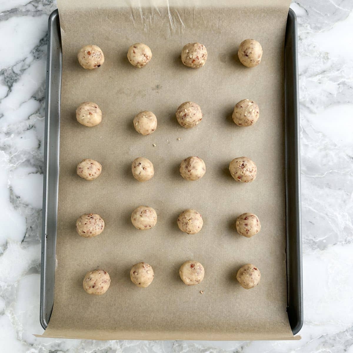 Unbaked snowball cookies on a baking sheet.