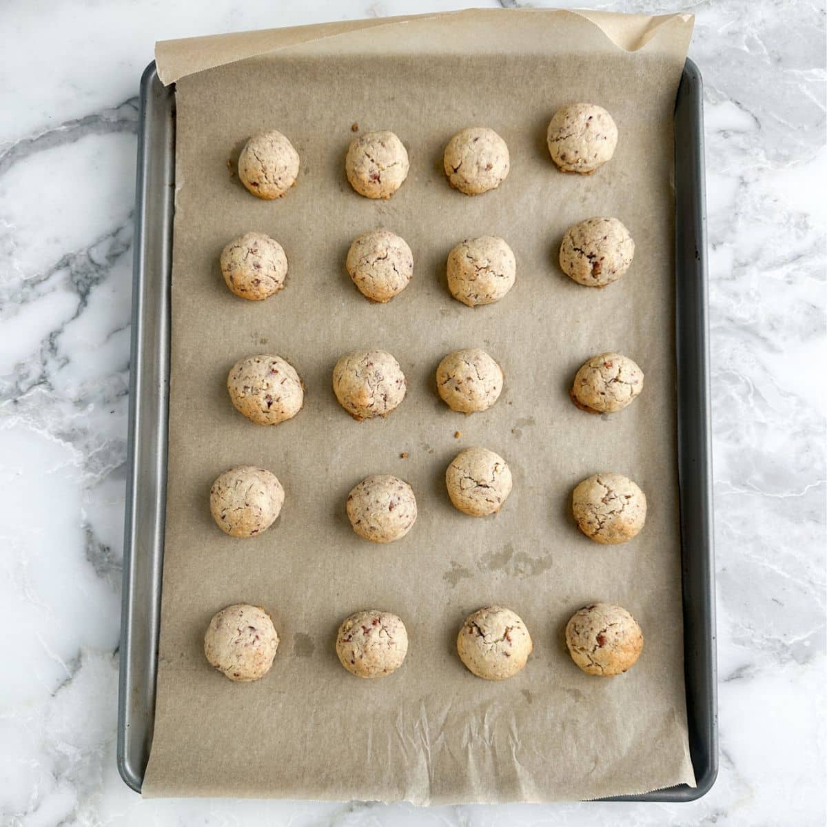 Baked pecan balls on a baking sheet.