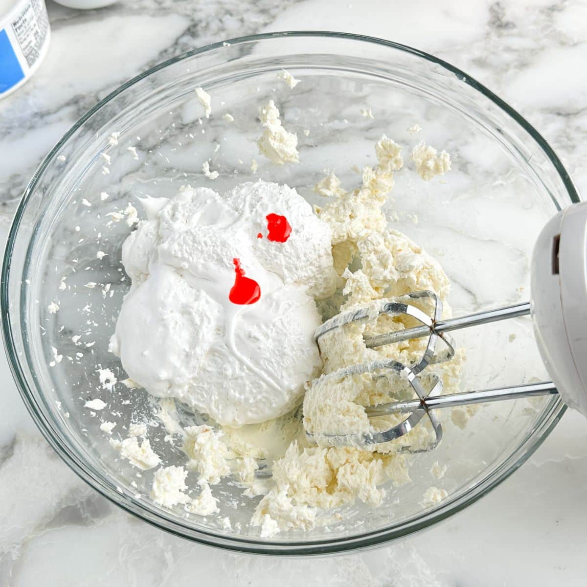 Bowl of cream cheese, marshmallow fluff, and pink food coloring. 