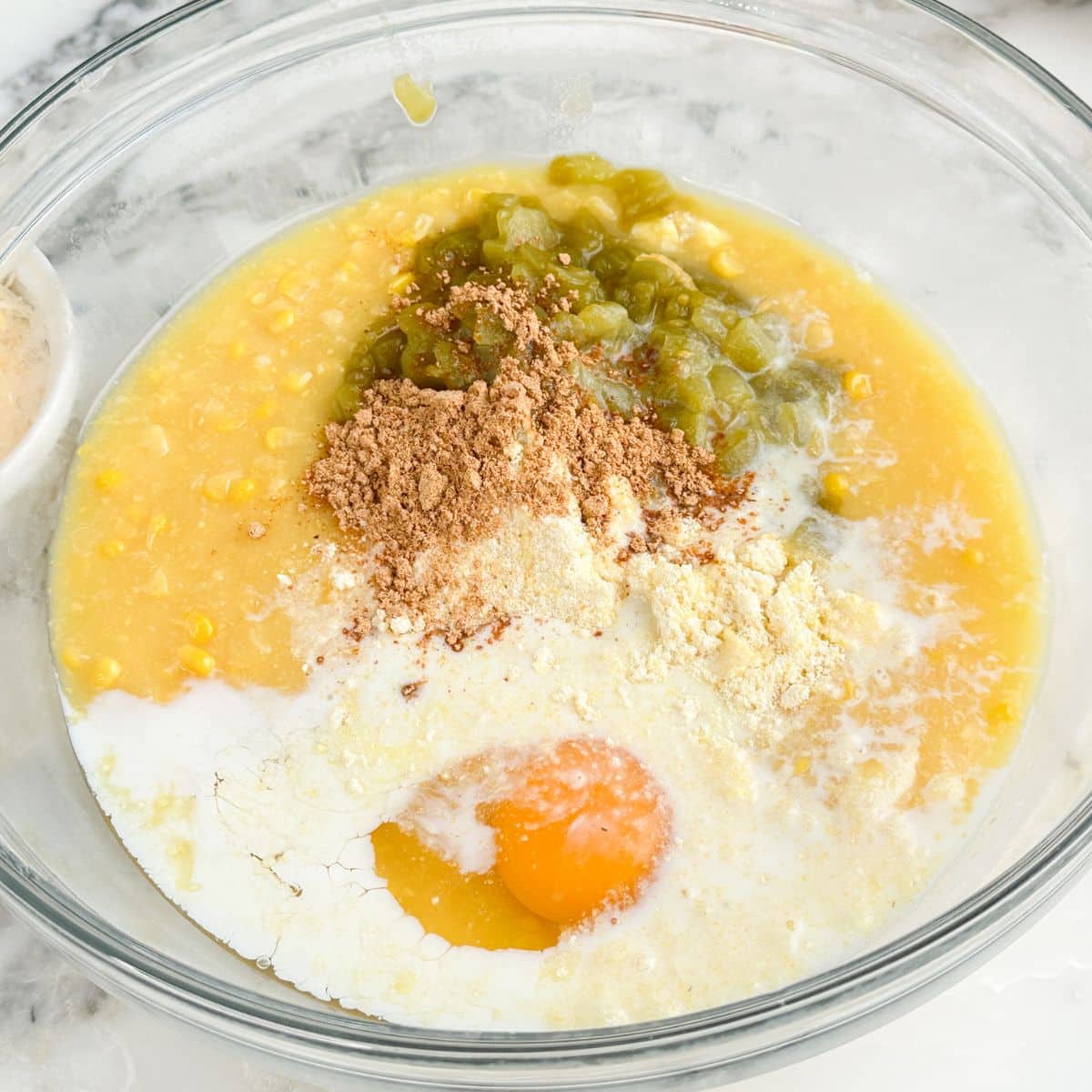 Bowl with egg, seasoning, milk, corn, and green chiles.