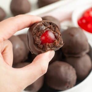 Hand holding a chocolate covered cherry bite.