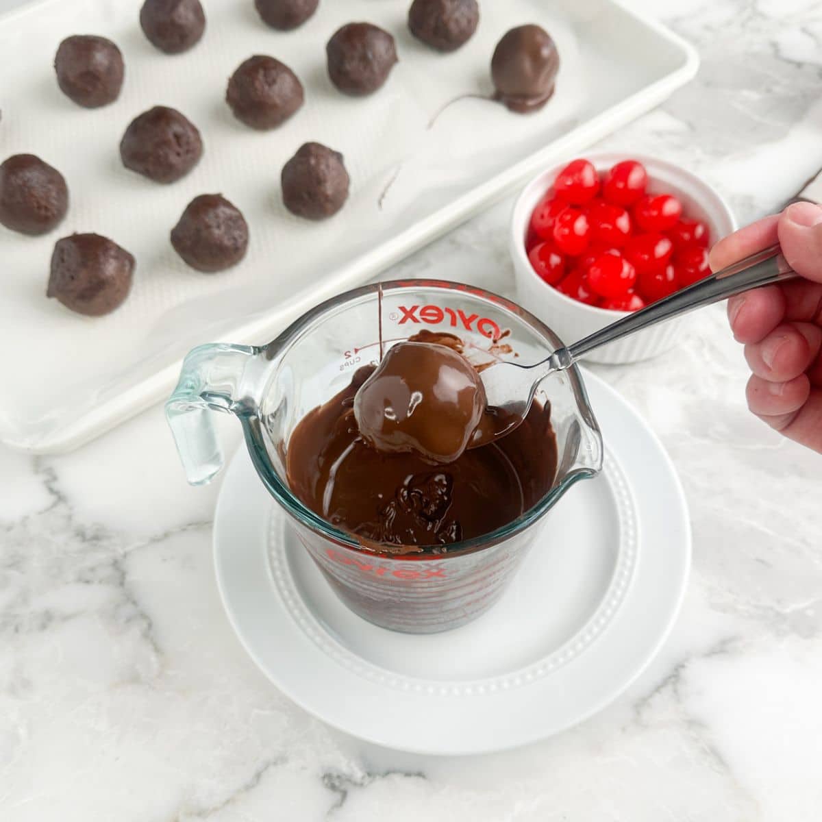 Brownie bite being dipped into melted chocolate. 