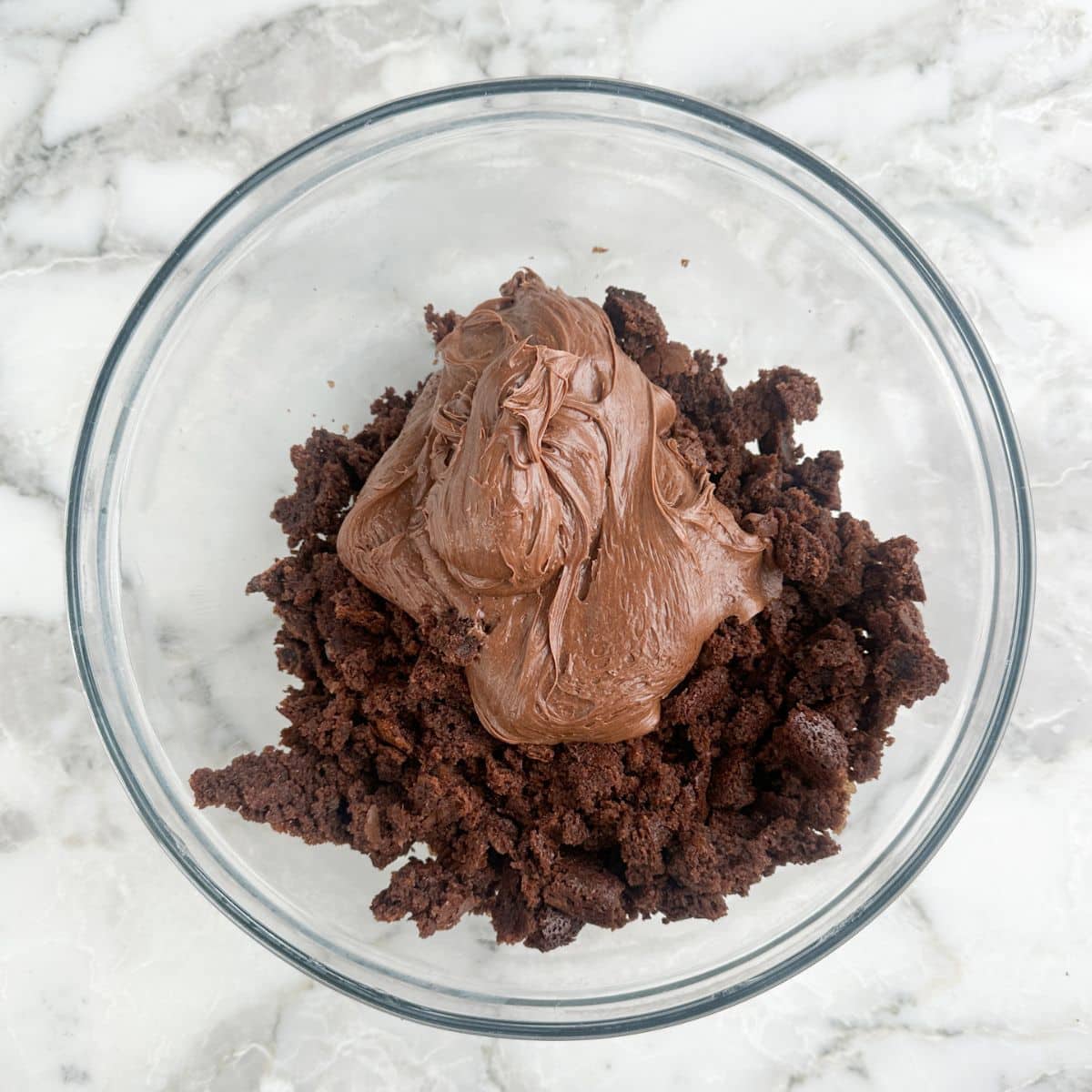 Bowl of crumbled brownie and chocolate frosting. 
