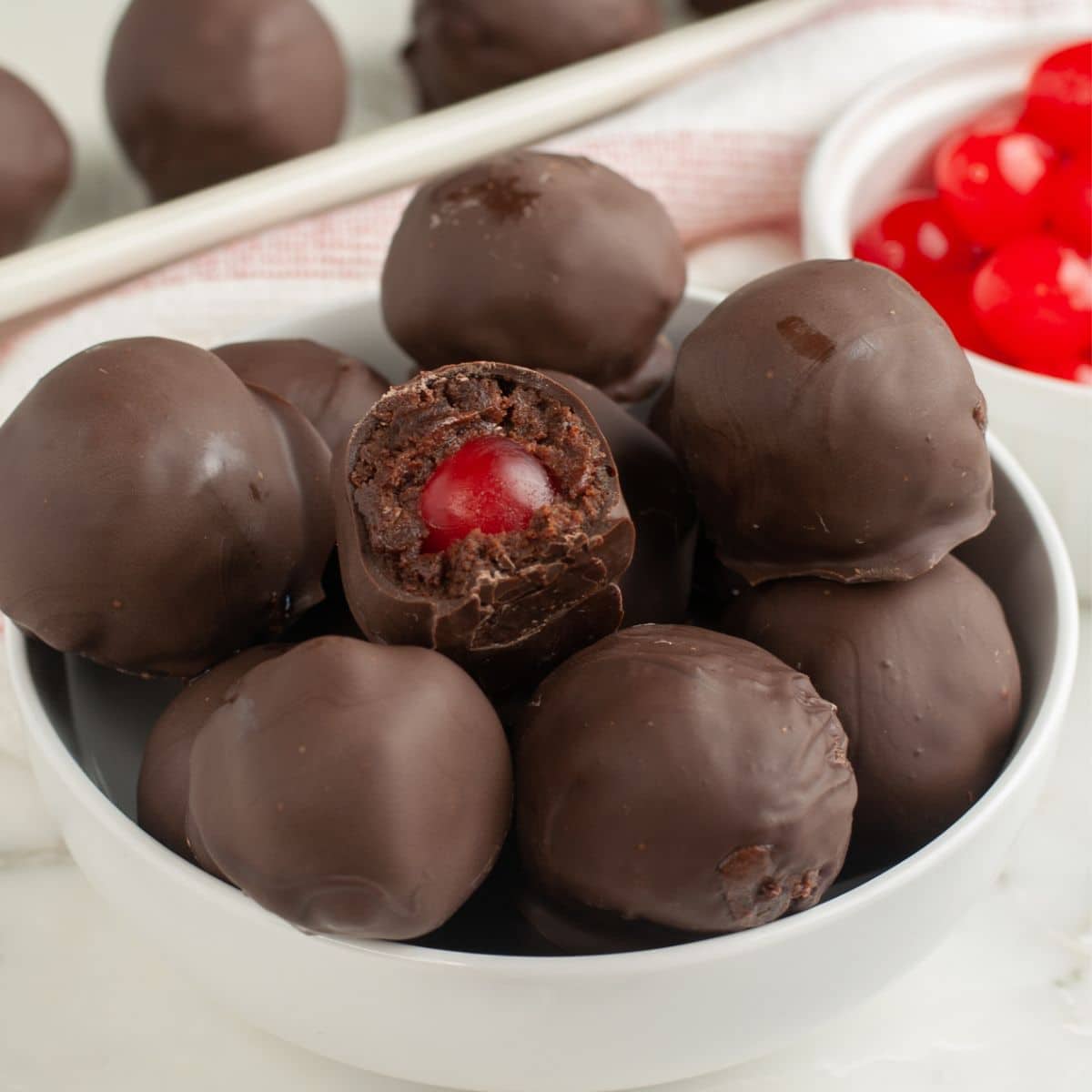 Bowl of chocolate covered brownie bites with a cherry center. 