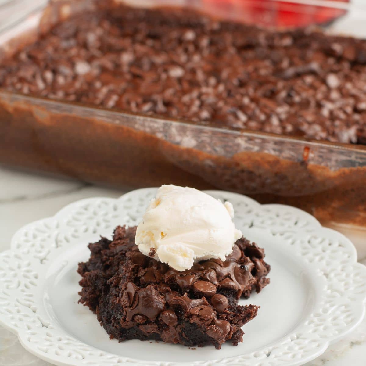 Plate with a piece of chocolate cake topped with vanilla ice cream. 