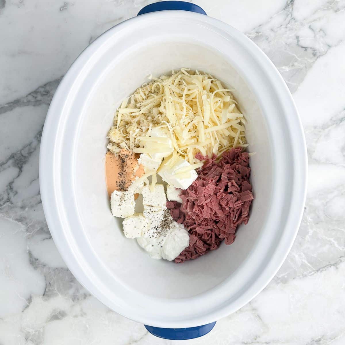 Slow cooker with cream cheese, diced corned beef, shredded Swiss cheese, and Thousand Island dressing.