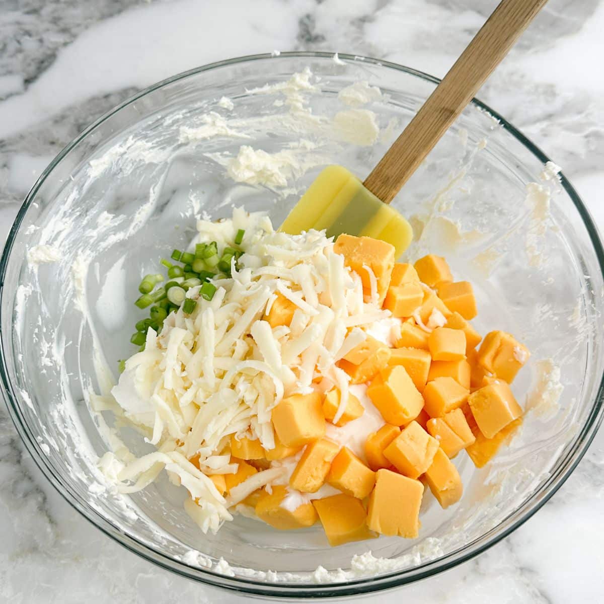 Bowl of cream cheese, Velveeta cheese, Monterey jack cheese, and diced onions.