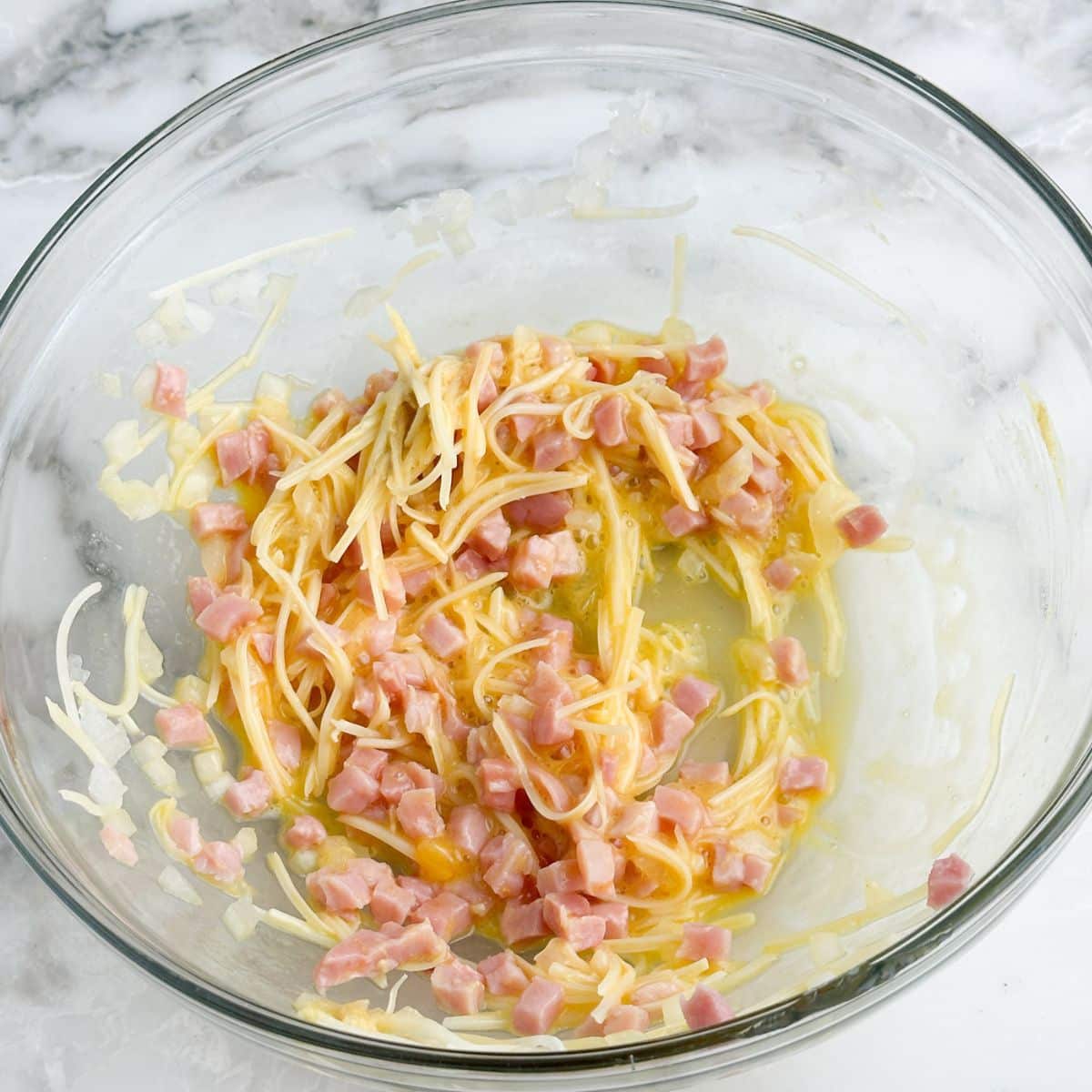 Bowl with shredded cheese and diced ham. 