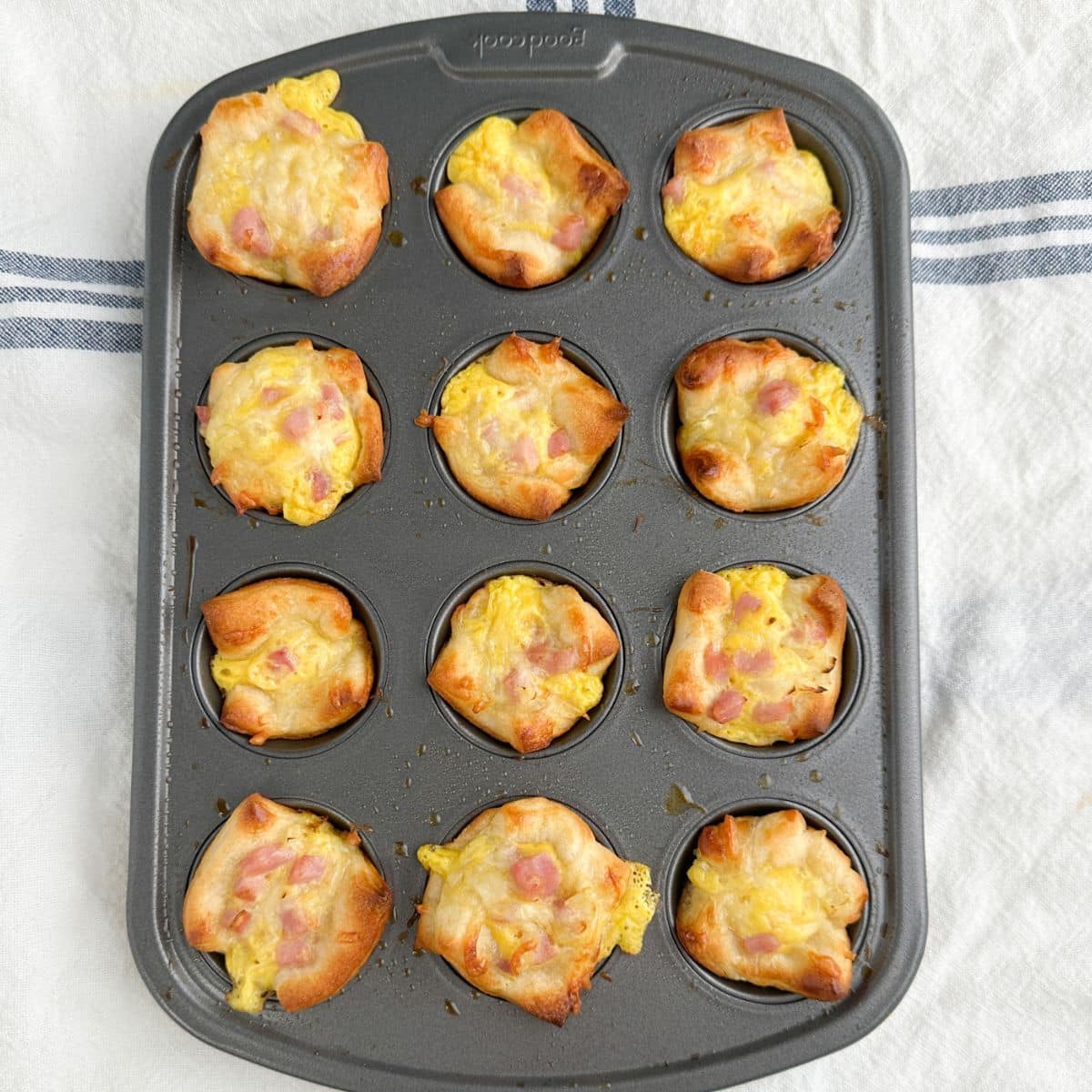 Mini muffin tin with baked ham puffs. 