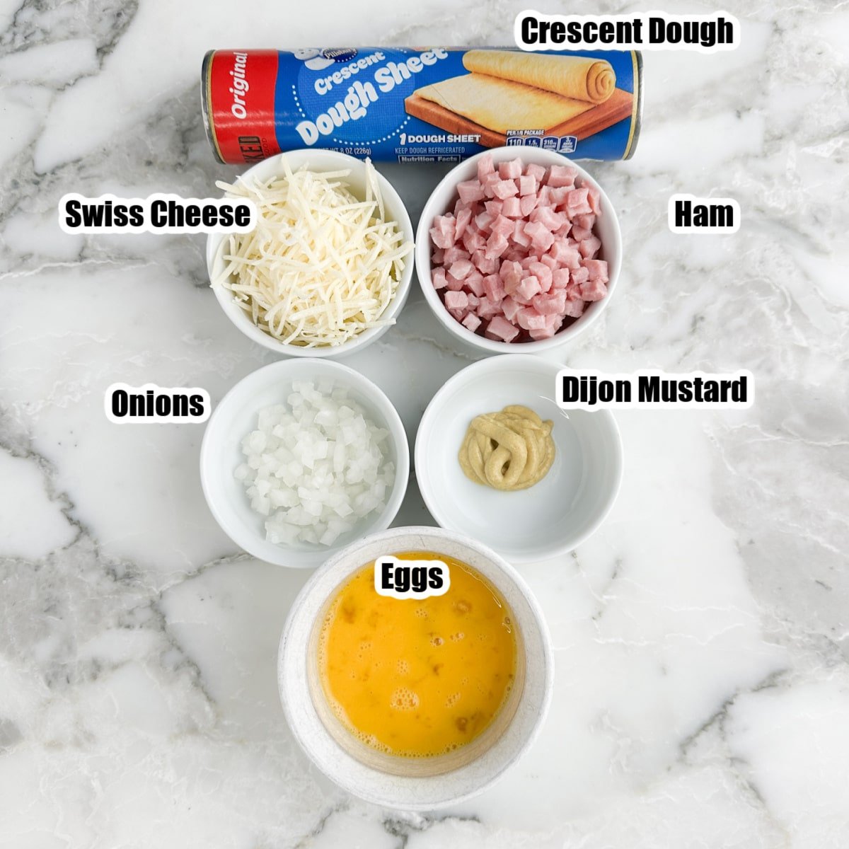 Can of crescent dough, bowls of cheese, ham, onions, egg, and mustard.