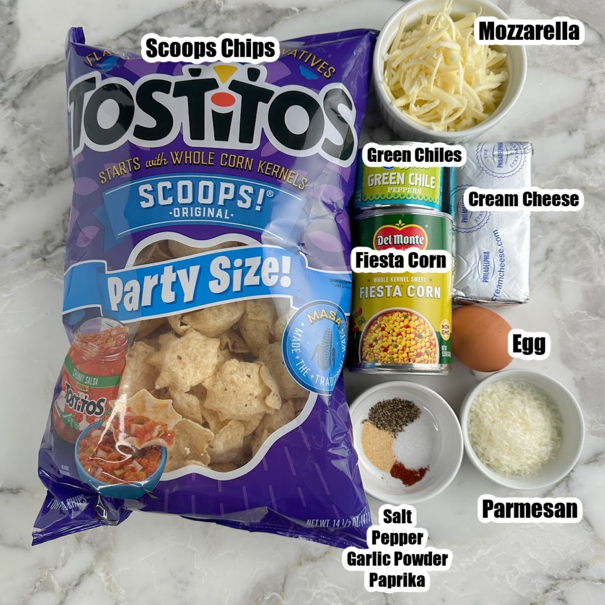 Bag of Scoops chips, bowl of shredded cheese, cream cheese, fiesta corn, green chiles, and seasonings.