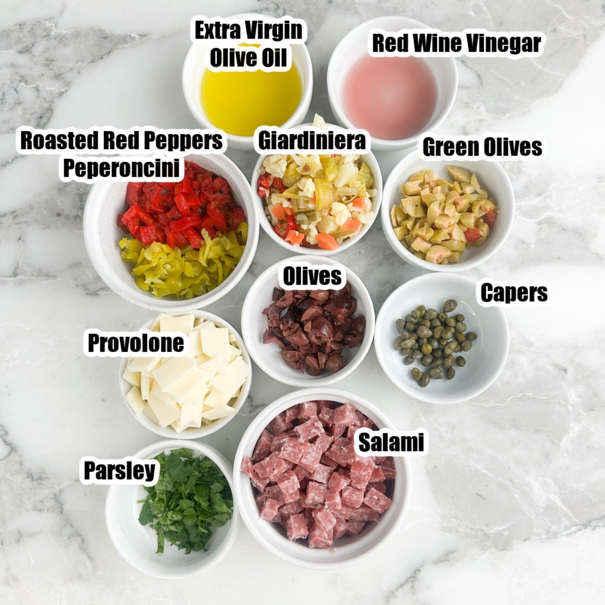 Bowl of salami, provolone, capers, oil, vinegar, olives, and parsley.