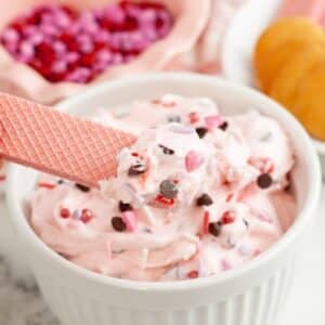 Bowl of pink booty dip with a pink cookie dipping in.