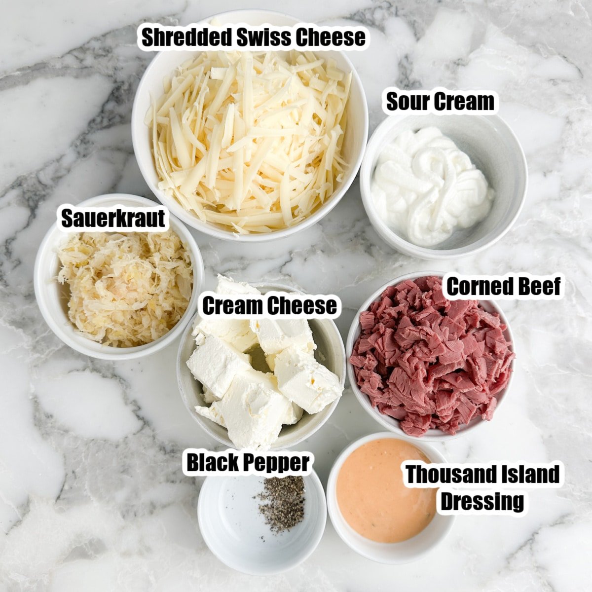 Bowl of shredded Swiss cheese, sauerkraut, sour cream, corned beef, cream cheese, and Thousand Island.