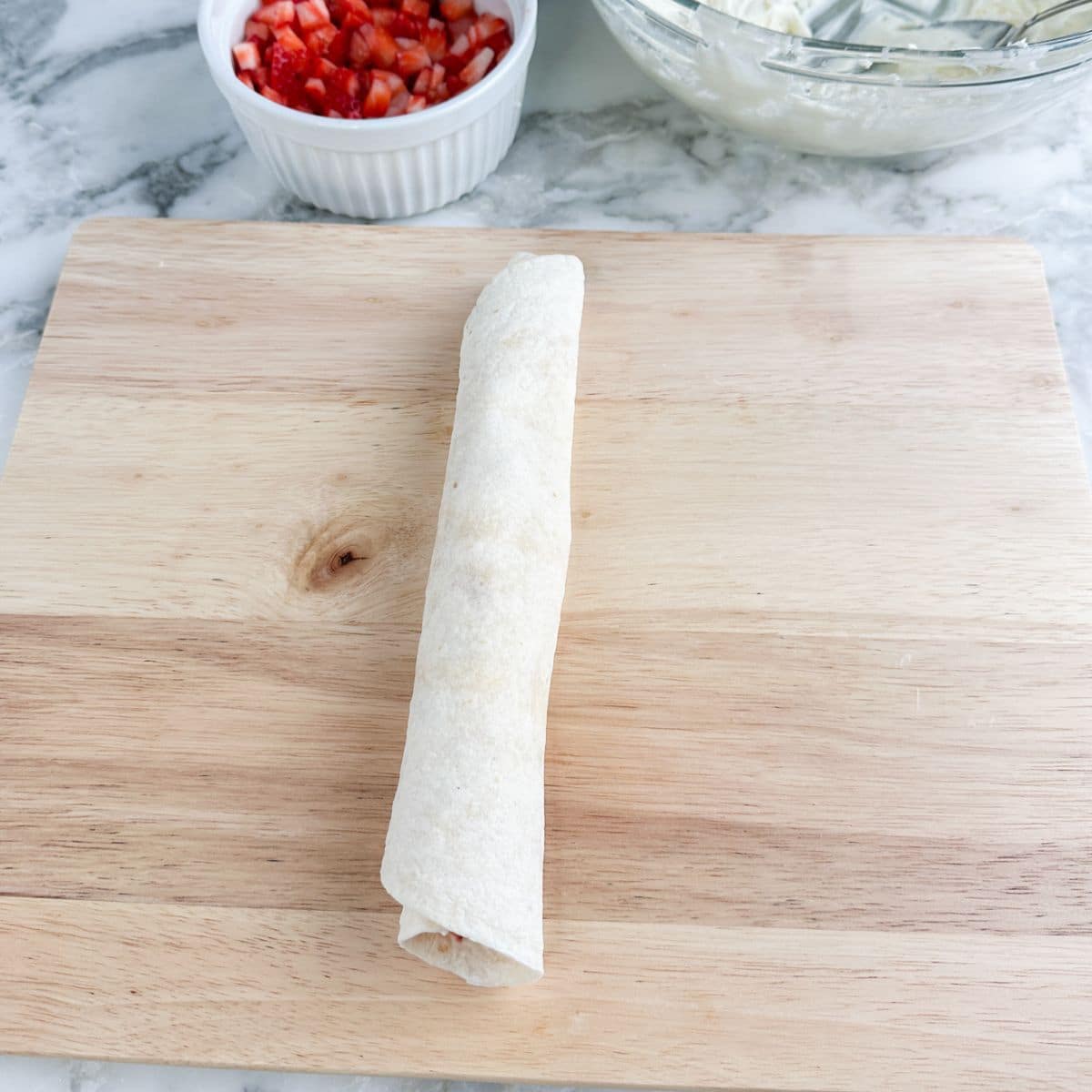 Rolled up tortilla on a cutting board. 