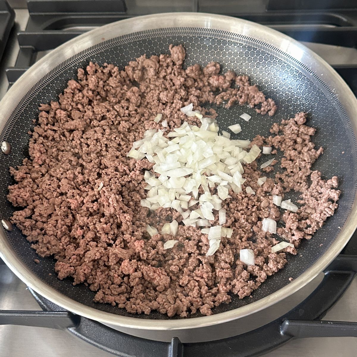 Skillet with ground beef and diced onions.