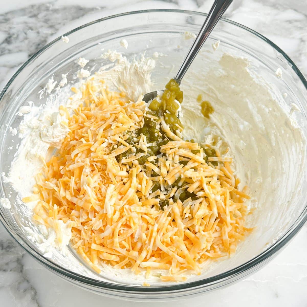 Bowl of whipped cream cheese, shredded cheese, and green chiles.