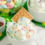 A bowl of marshmallow dip with a graham cracker.