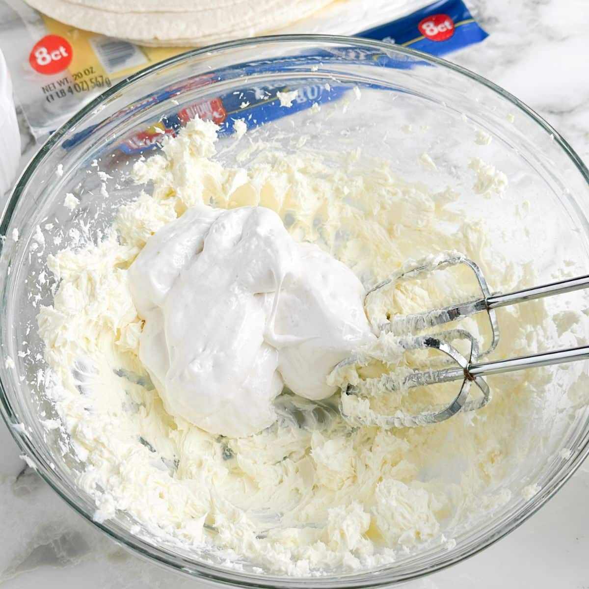 Bowl of cream cheese and marshmallow creme with a mixer. 