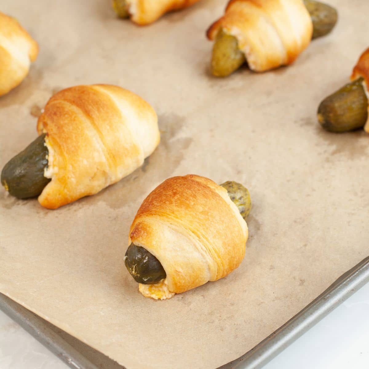 Baking pan with pickles in a blanket. 