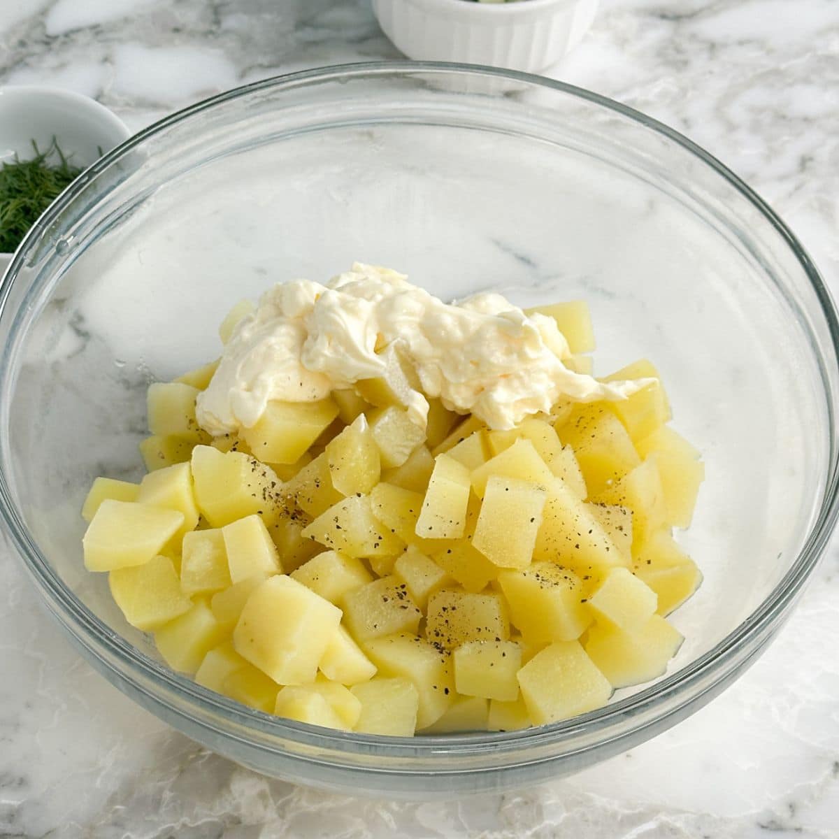 Bowl with diced potatoes and mayonnaise. 