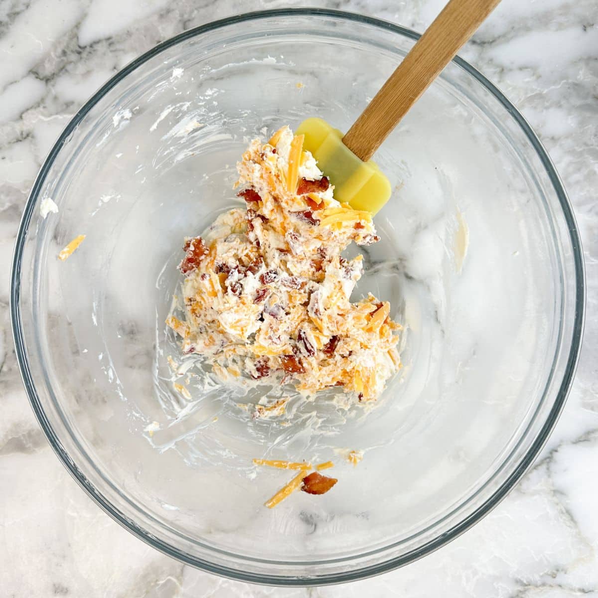 Bowl of cream cheese, shredded cheese, and crumbled bacon. 