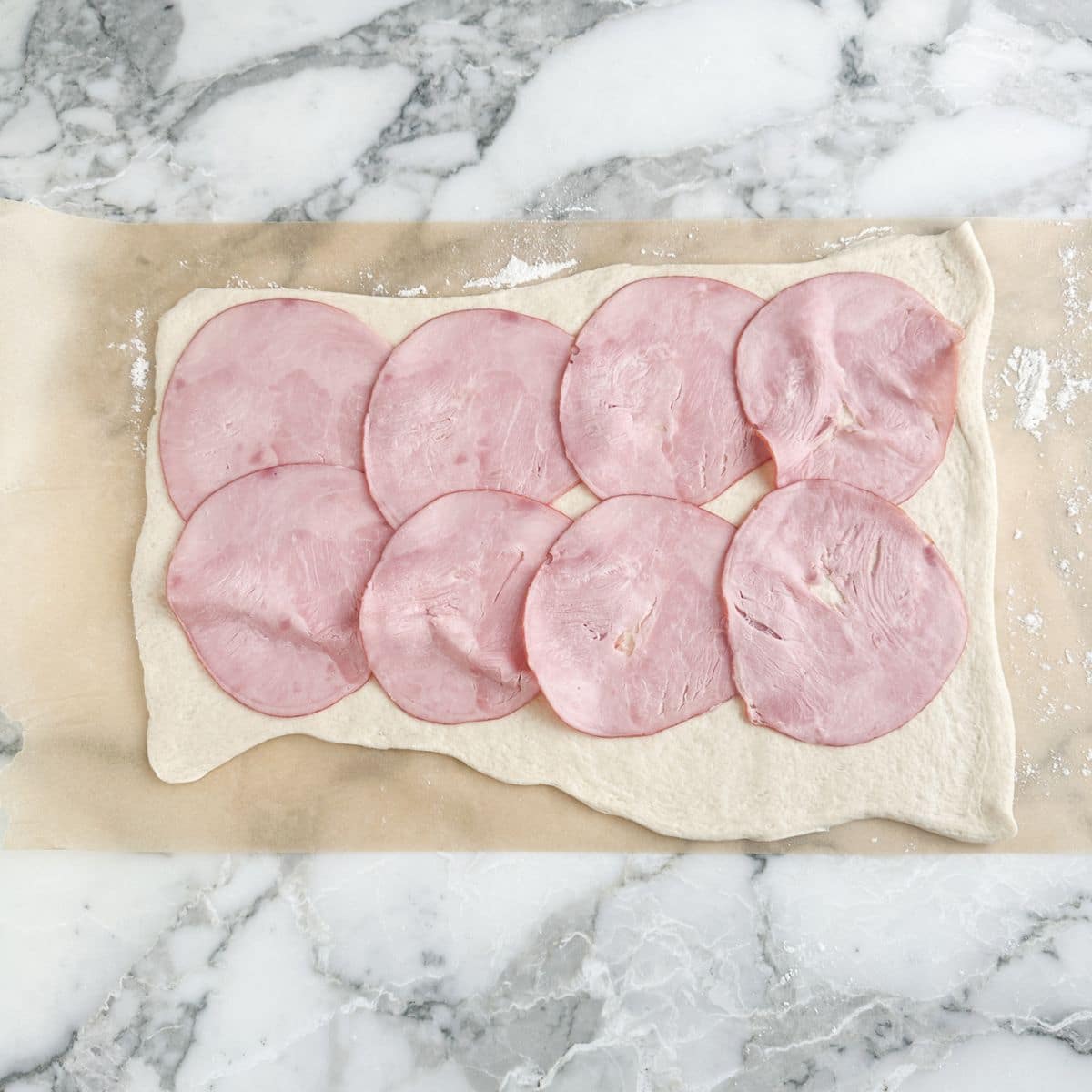 Pizza dough topped with deli ham. 