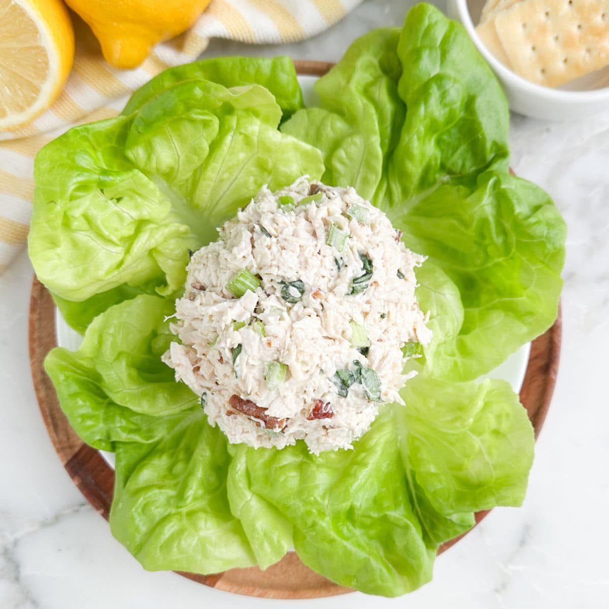 A scoop of lemon basil chicken salad on a bed of lettuce leaves.