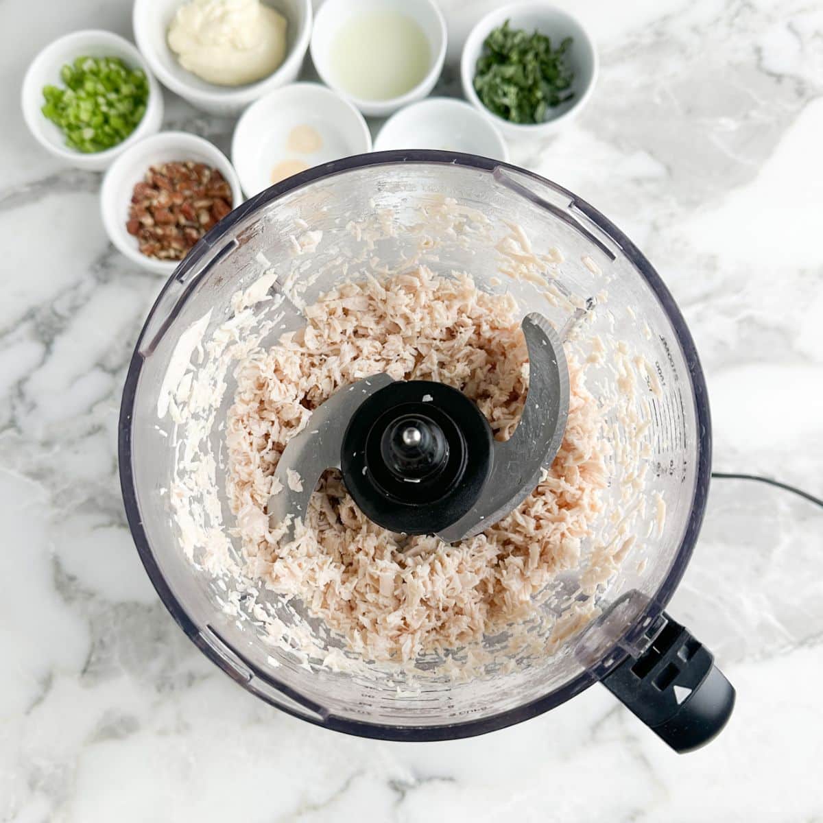 Food processor with shredded chicken.