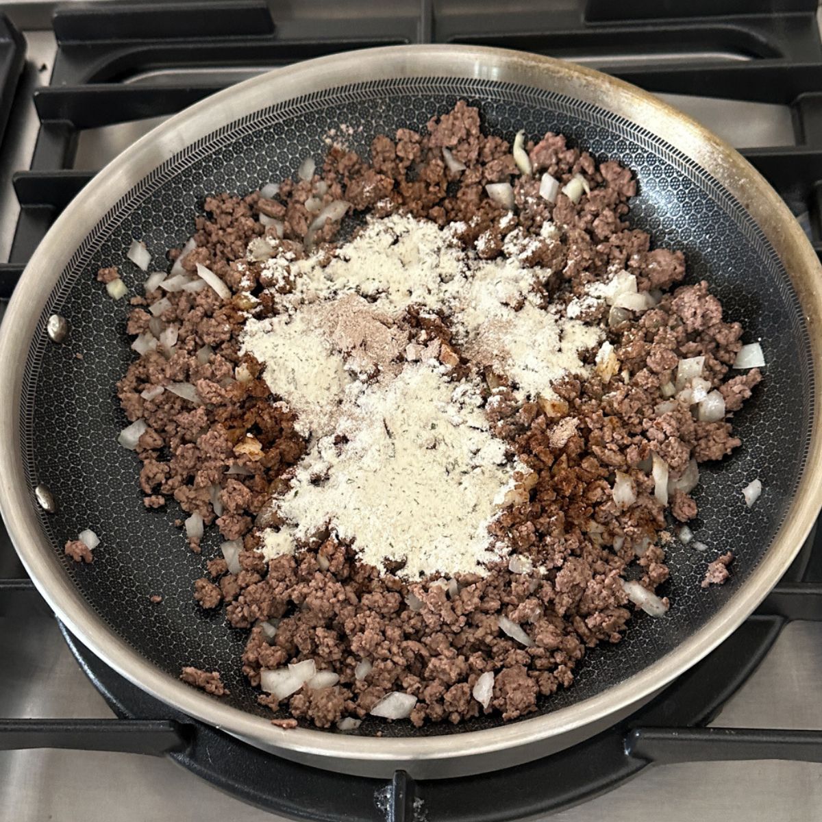 Skillet with ground beef, diced onions, and ranch seasoning.
