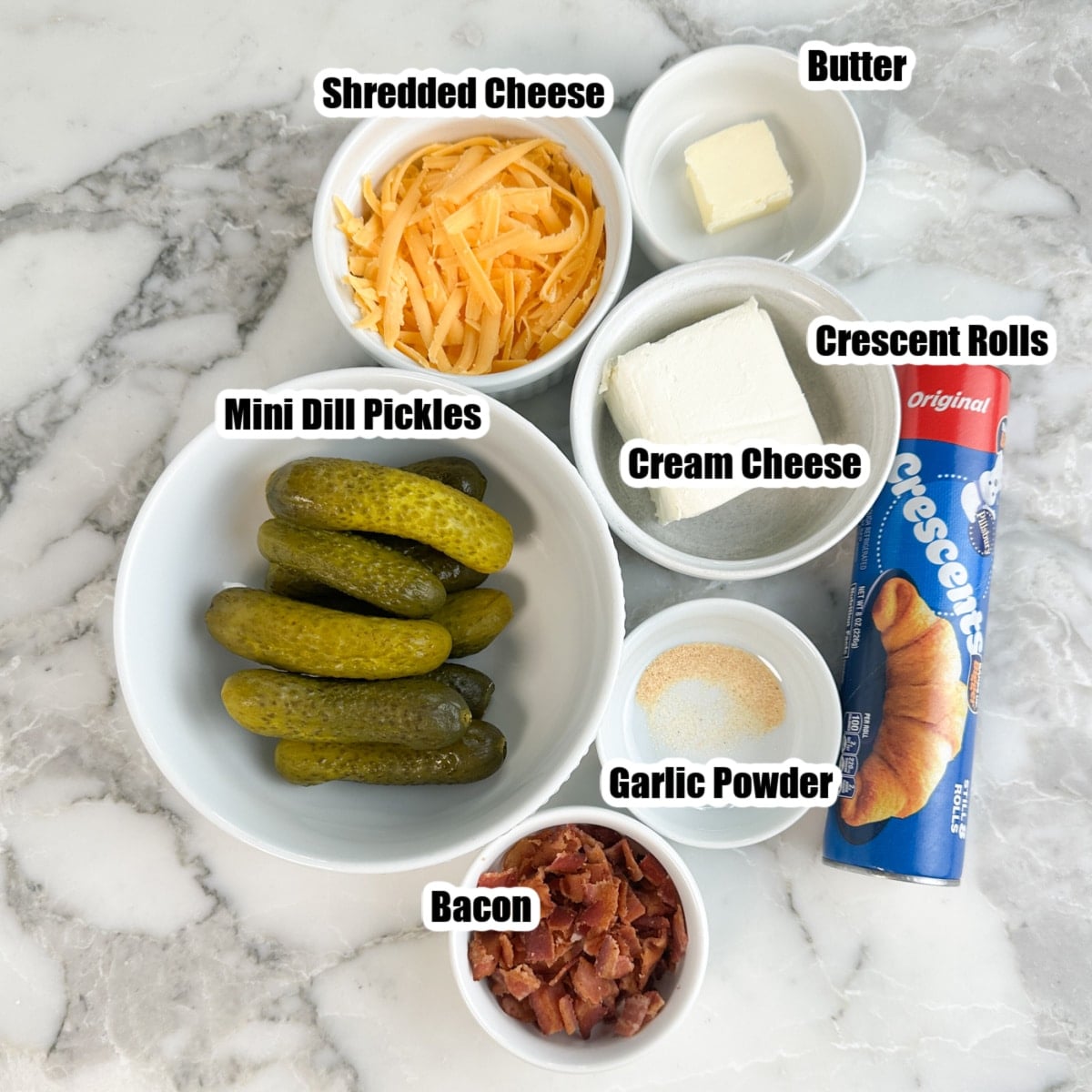 Bowl of baby pickles, shredded cheese, crumbled bacon, cream cheese, butter, and crescent rolls. 