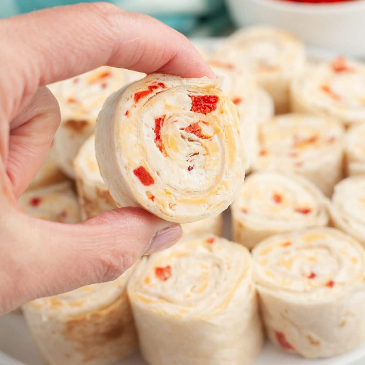 Hand holding pimento cheese pinwheel. 