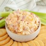 Bowl of pimento cheese surrounded by crackers.