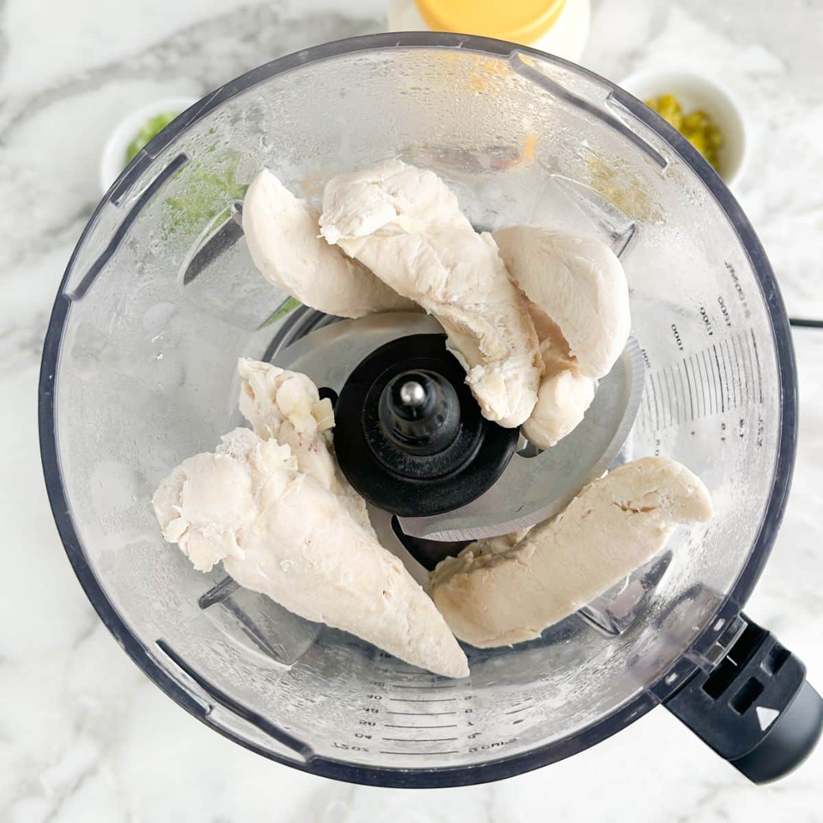 Food processor with cooked chicken tenders. 