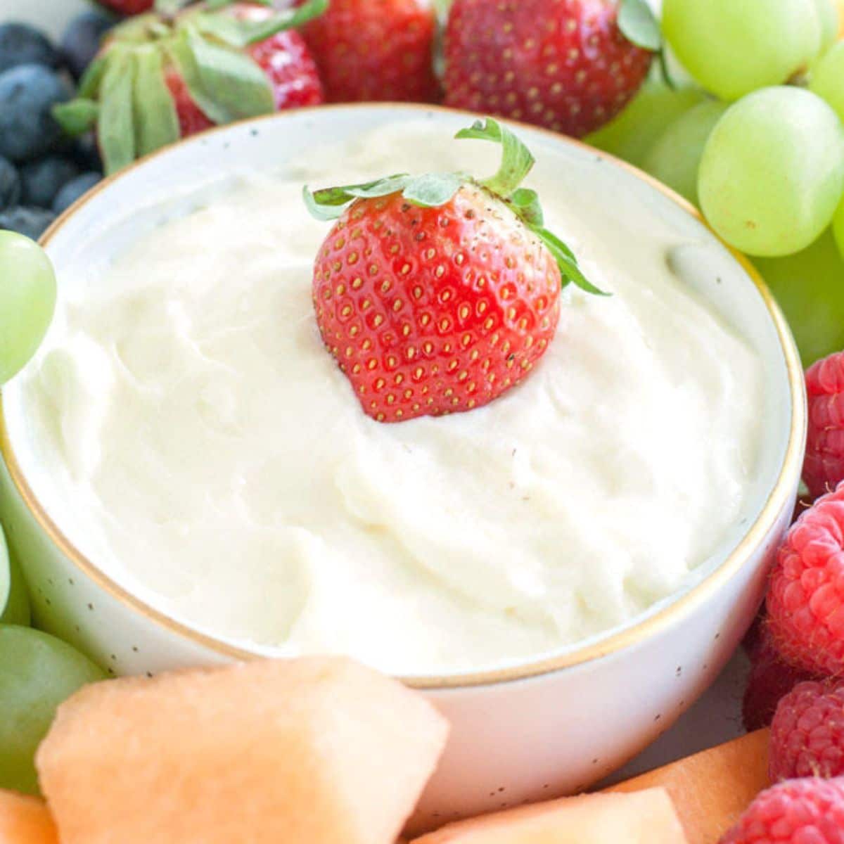 Bowl of fruit dip surrounded by fruit.