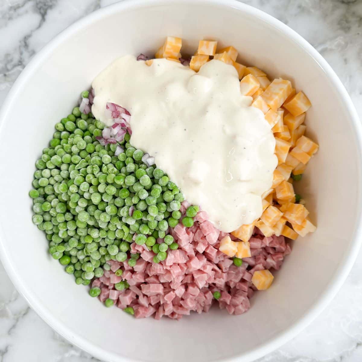 Bowl of peas, ham, cheese, and dressing. 