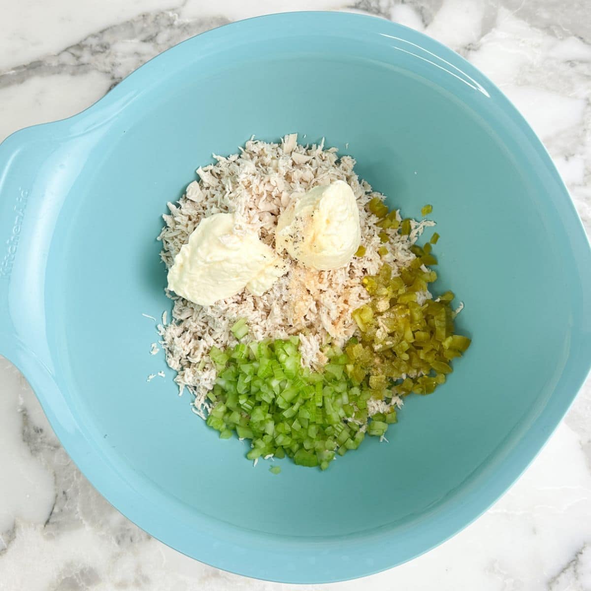 Bowl of shredded chicken, mayonnaise, diced celery, and diced jalapenos. 