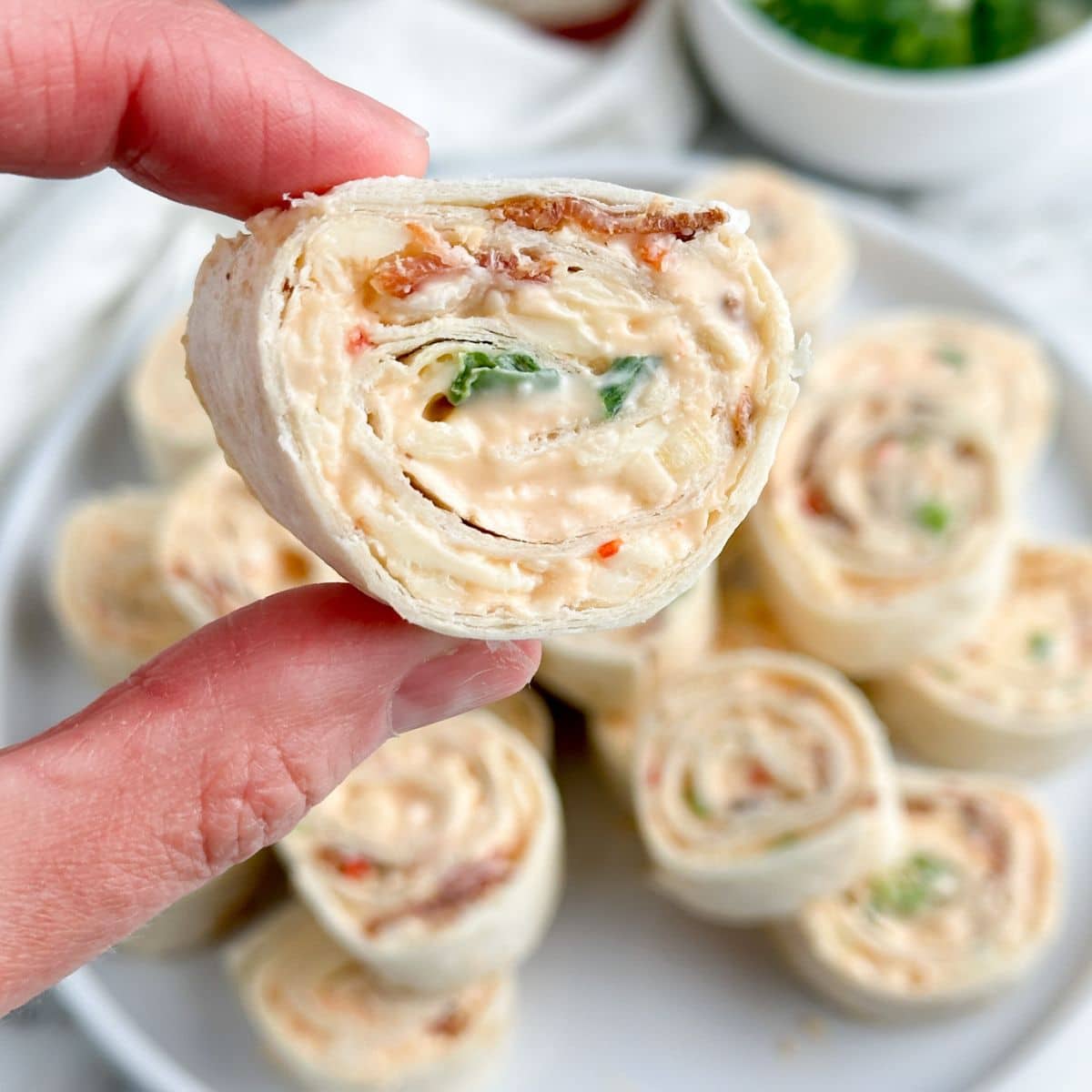 Hand holding pepper jelly pinwheel. 