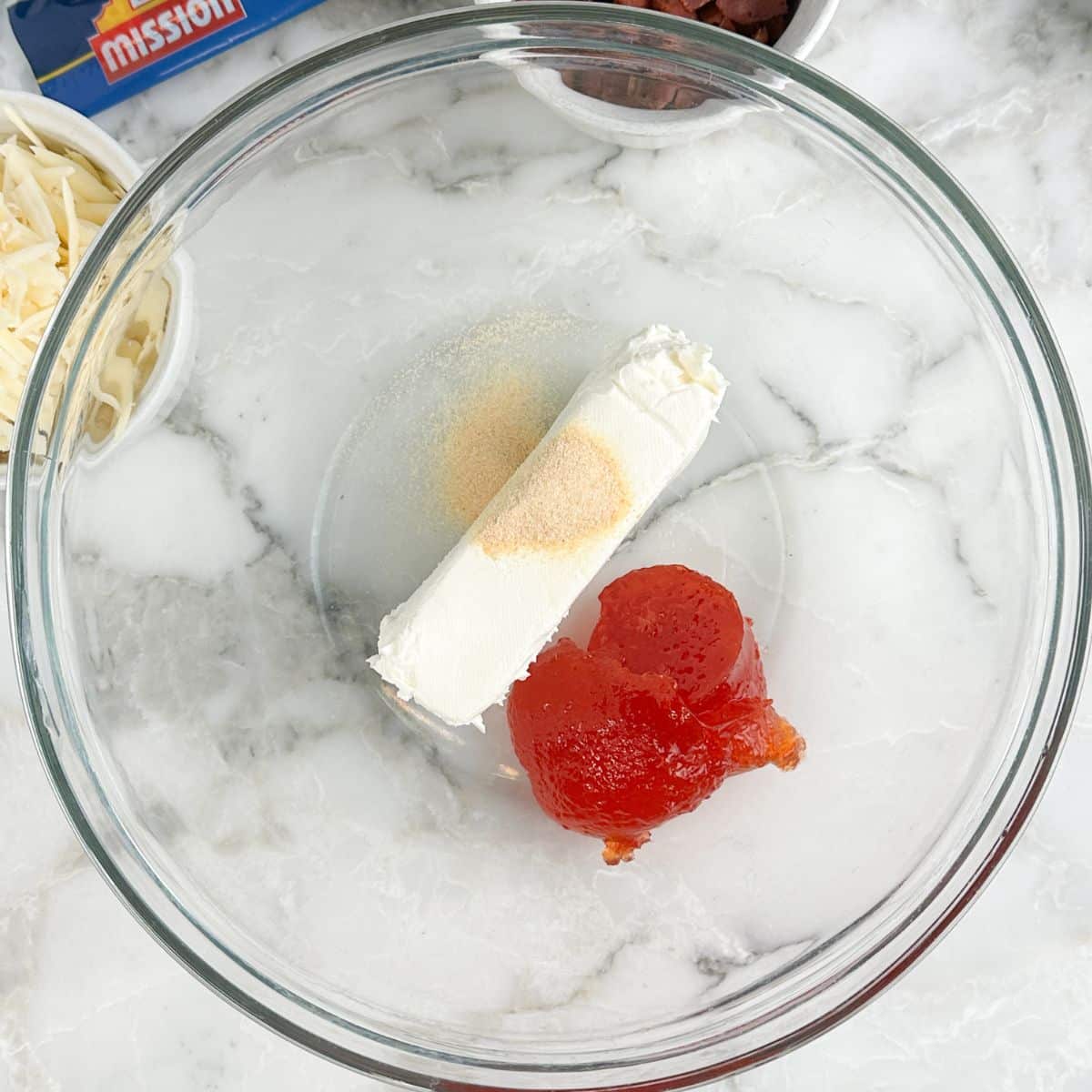 Bowl with cream cheese, garlic powder, and pepper jelly. 