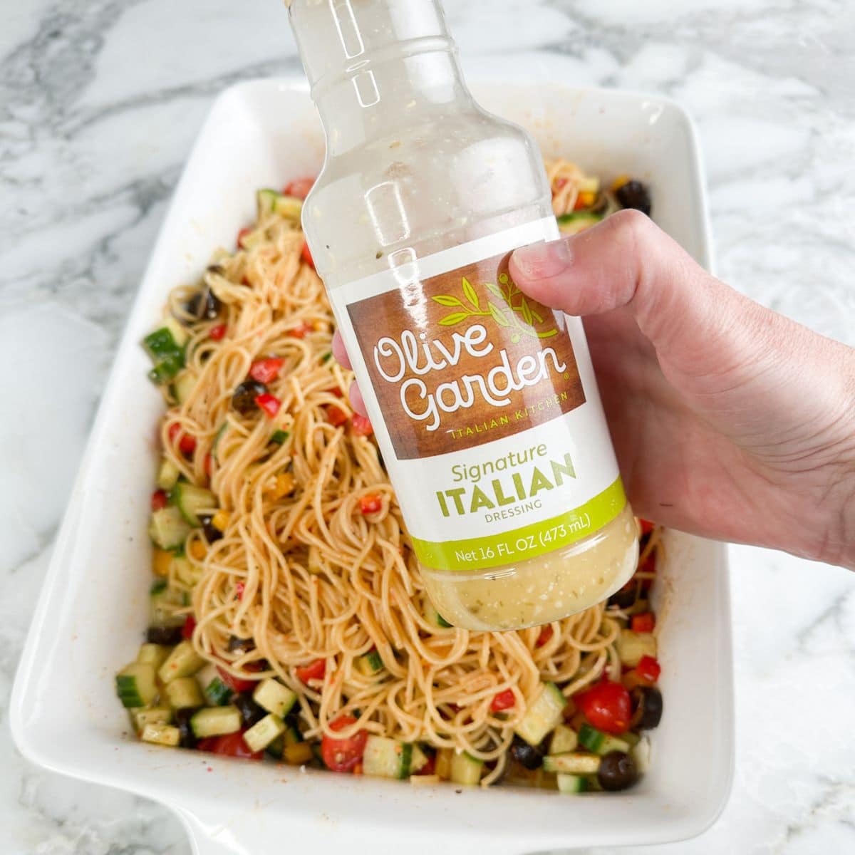 Hand holding a bottle of Italian dressing. 