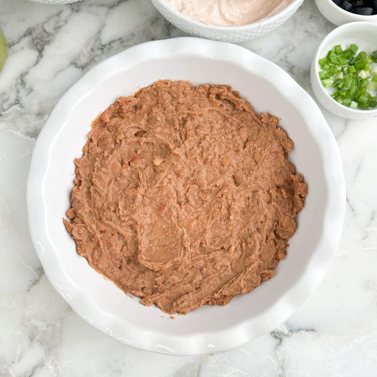 Refried beans spread in a pie dish.