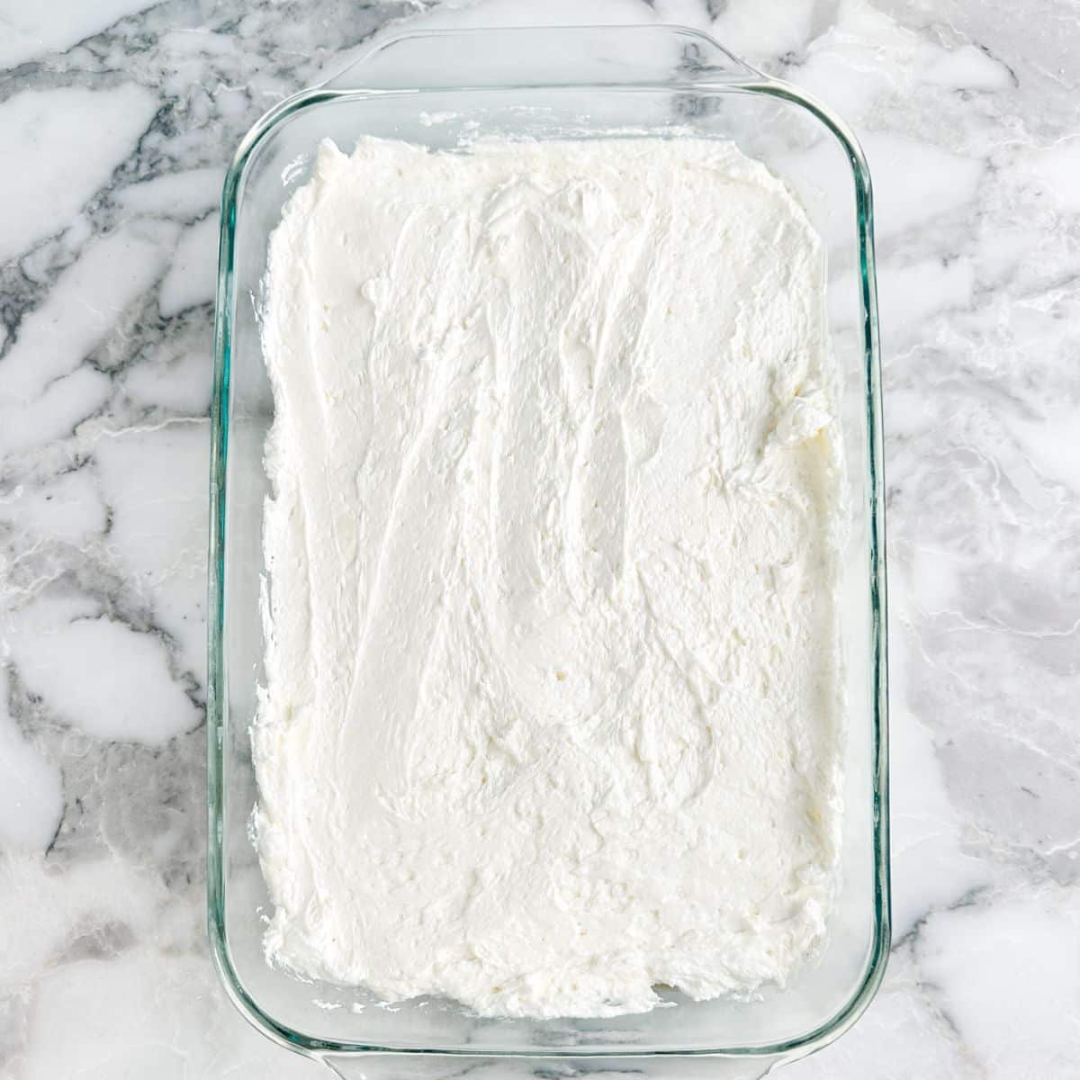 Baking dish with Cool Whip mixture spread in the dish.