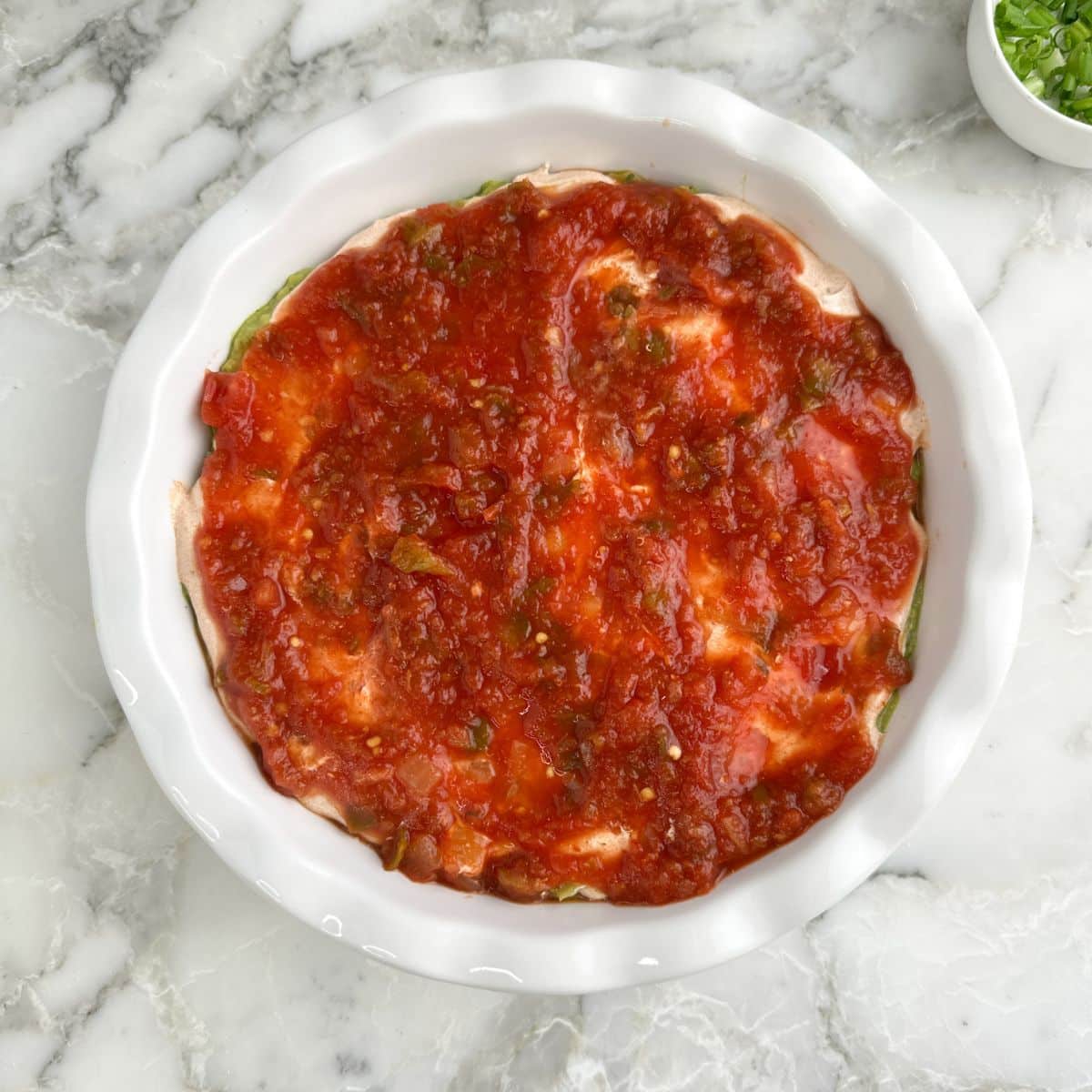 Pie dish with dip topped with salsa.