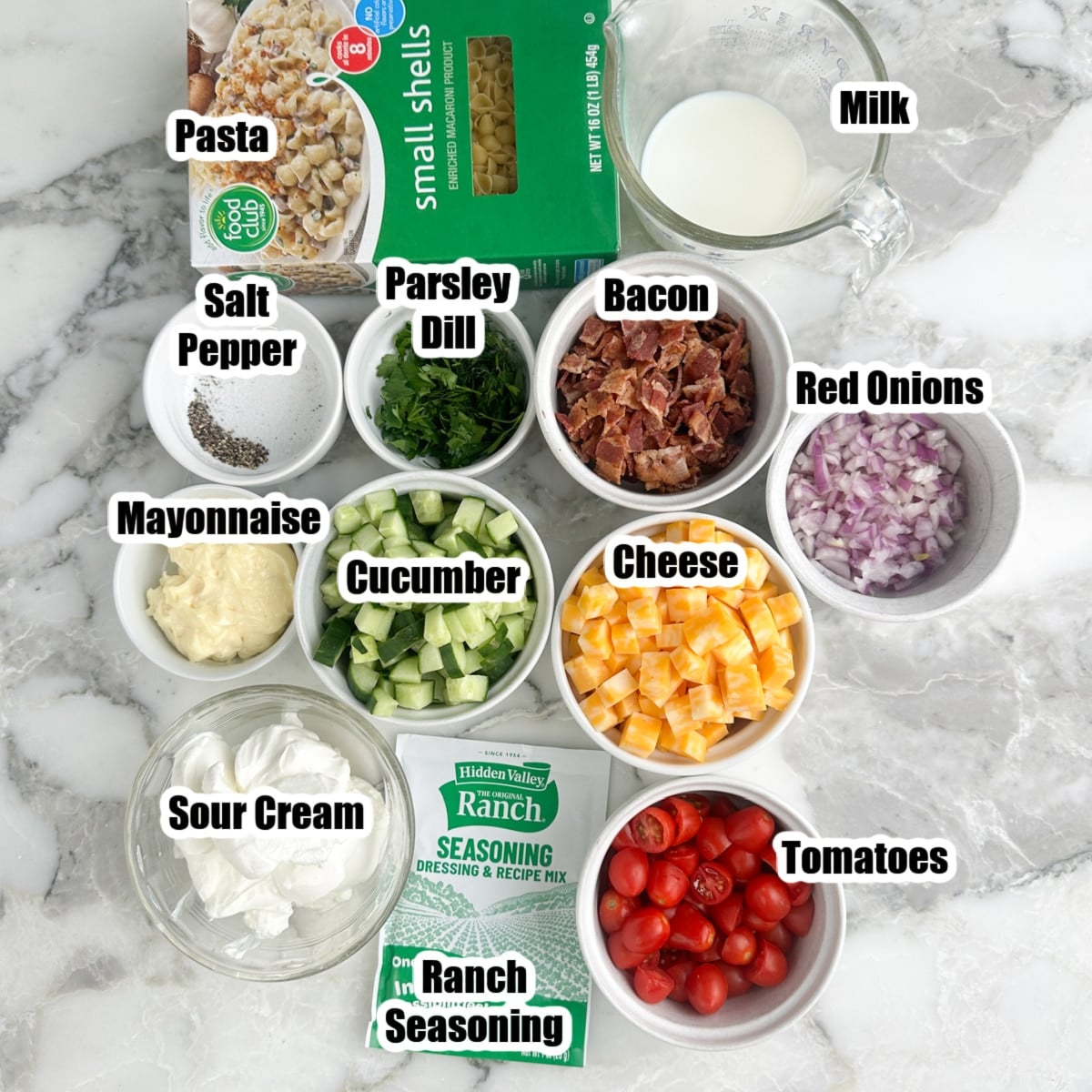 Box of pasta, bowl or may, sour cream, milk, bacon, onions, cucumbers, cheese, herbs, and ranch seasoning.