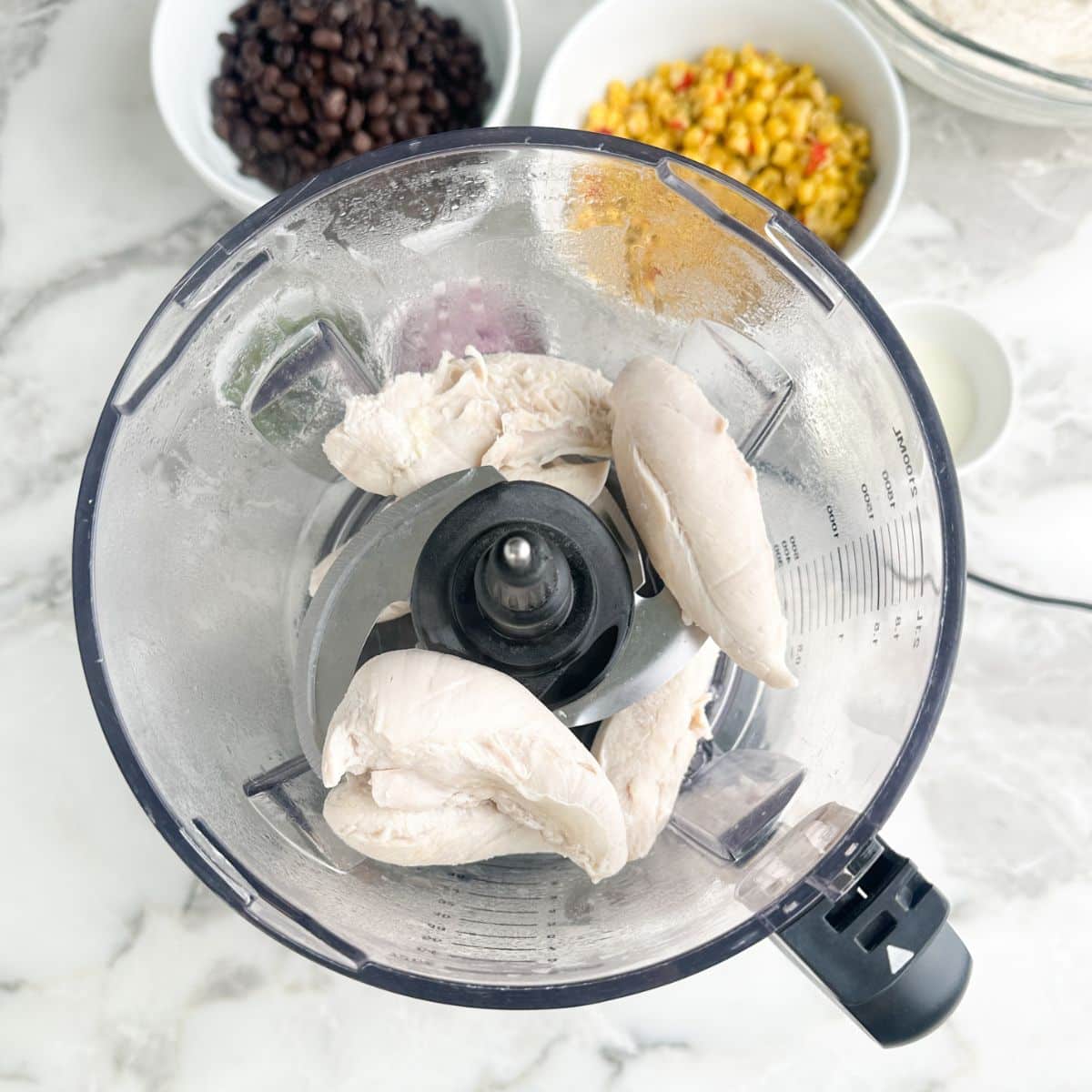 Cooked chicken tenders in a food processor.