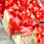 Spoon with pudding topped with diced strawberries.