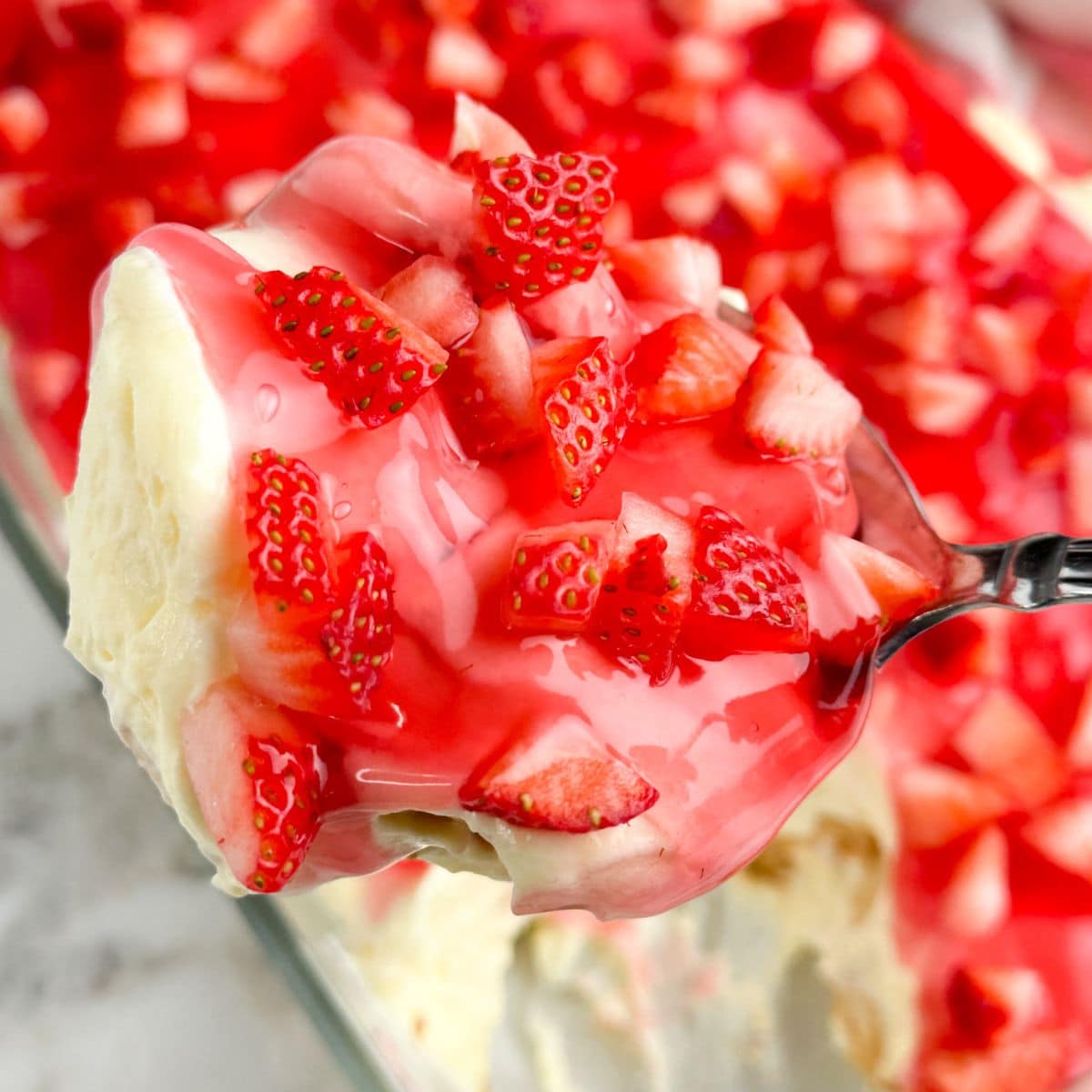 Spoon with pudding topped with diced strawberries. 