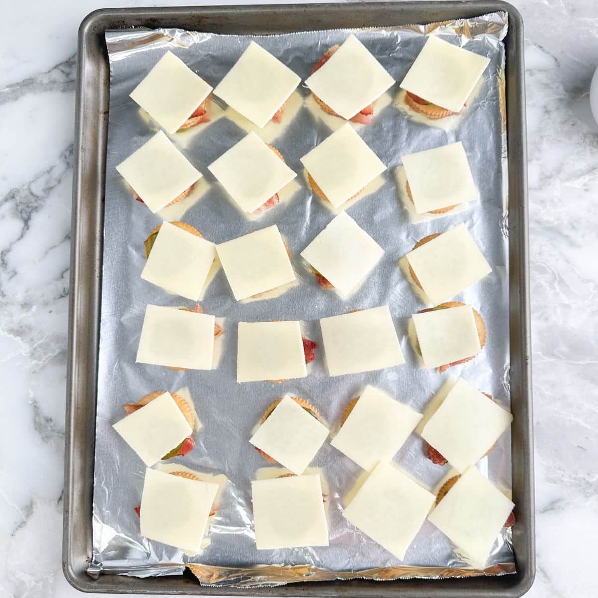 Crackers topped with bacon, pickles, and cheese.