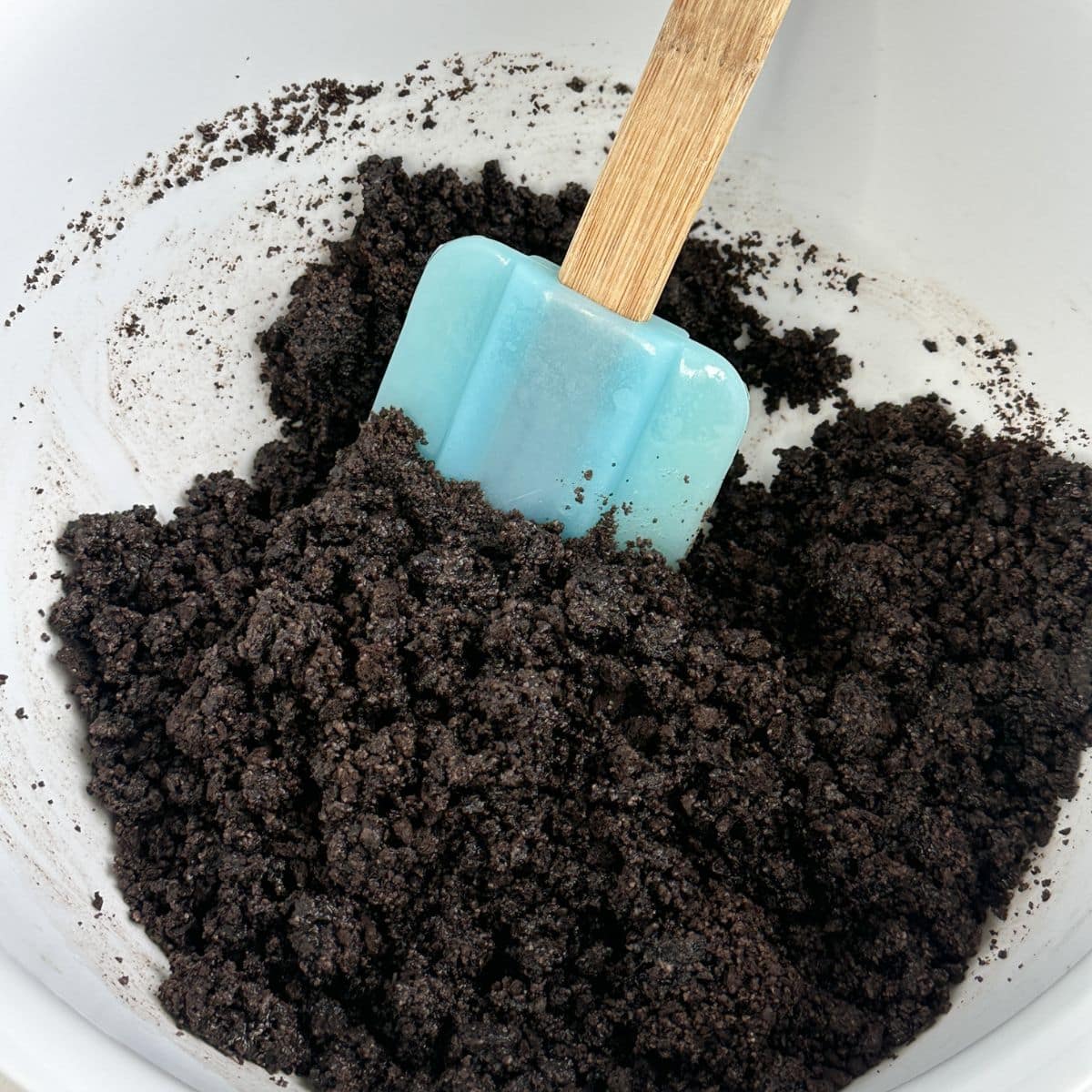 Bowl with Oreo crumbs and a spatula. 
